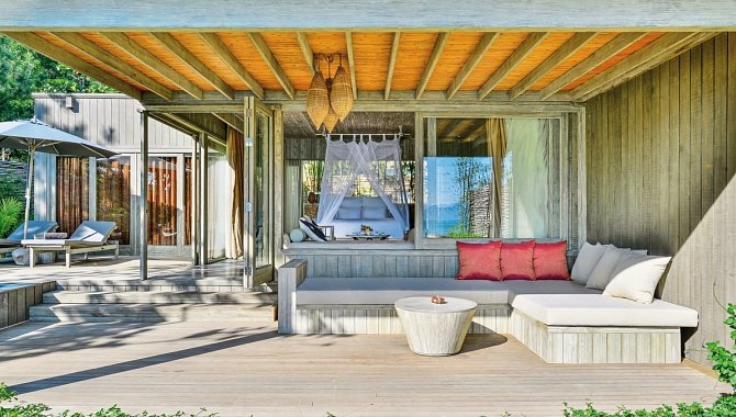 Terrasse mit überdachtem Sitzbereich und Blick ins Schlafzimmer mit Himmelbett.
