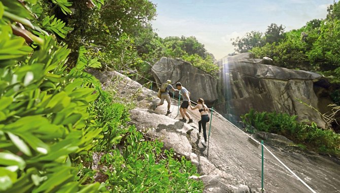 Gruppe von Menschen beim Klettern an einem felsigen Hang mit Seilen als Hilfe.