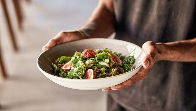 Eine große Porzellan Schüssel mit frischem Salat. Wird vom personal überreicht.
