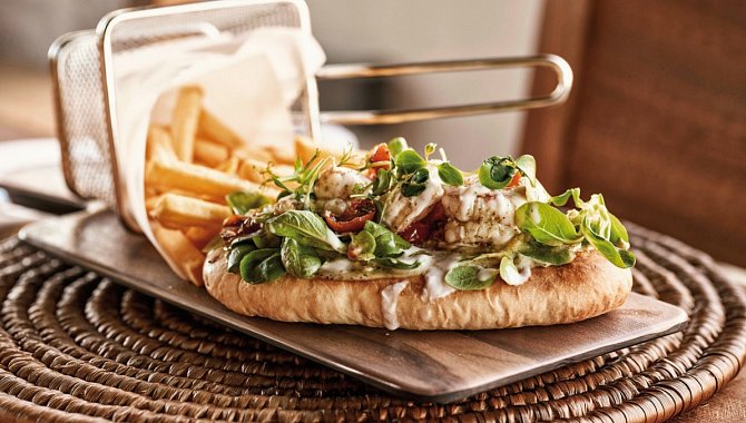 Ein Pitabrot, belegt mit frischem Salat und Gemüse mit reichlich Sauce. Dazu werden Pommes serviert.