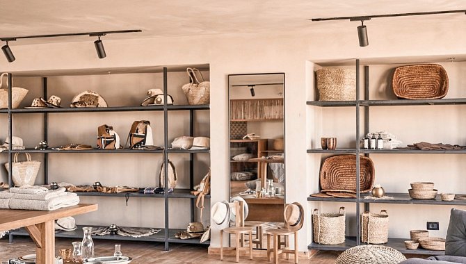 Graue Regale in einem Beigen Raum. In den Regalen stehen gewebte Gegenstände, wie verschiedene Körbe oder Sonnenhüte.
