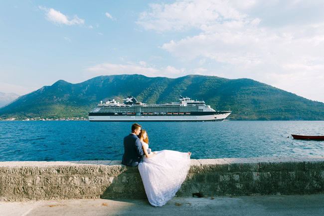 Ehepaar sitzt auf einer Mauer am Wasser