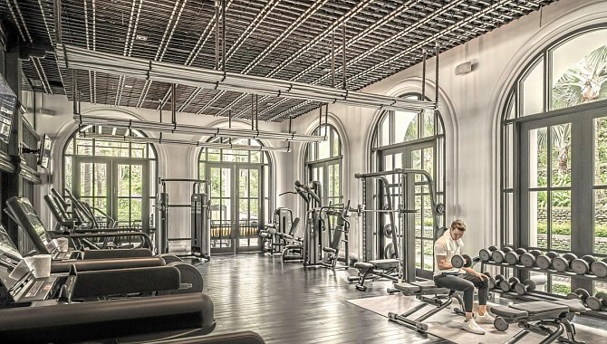 Fitnessstudio mit modernen Geräten und großen Fenstern zum Garten