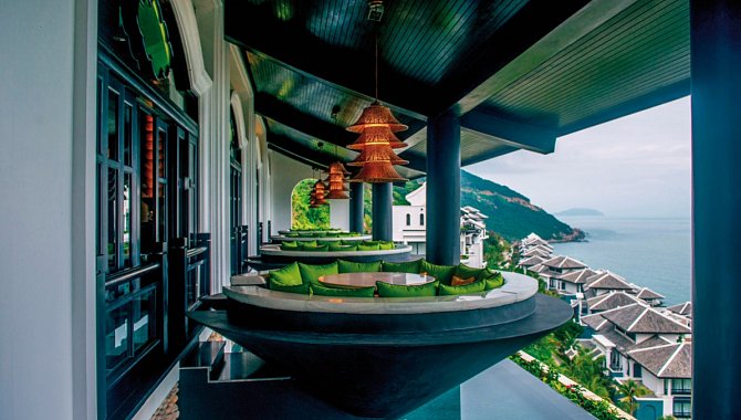 Sitznischen mit grünen Kissen auf einer Terrasse mit Blick auf das Meer