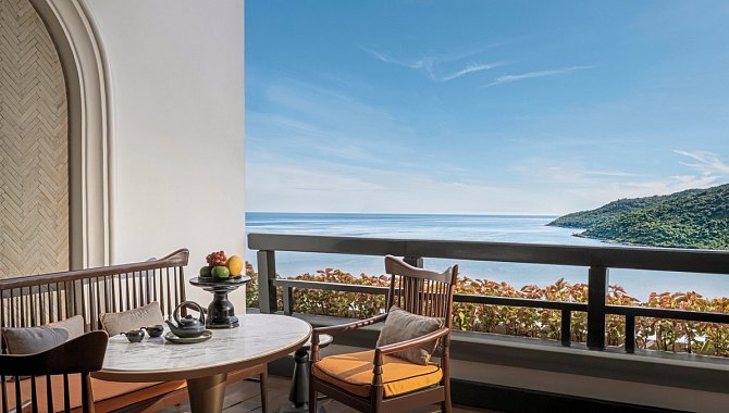 Balkon mit Tisch und zwei Stühlen, Blick auf das Meer und die grüne Küste