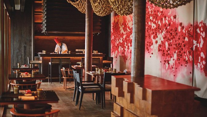 Ein Hotelrestaurant, dunkler gehalten mit offener Küche.