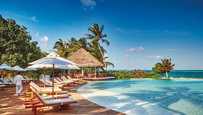 Holzsteeg am Meer. Mit Poolliegen und Sonnenschirmen.