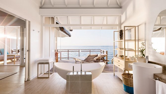 Badezimmer in einer Suite, die Glasfront lässt sich öffnen, sodass man von der Badewanne direkt auf das Meer schauen kann