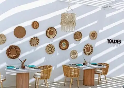 Der Helle Essbereich auf der Terrasse. Mit Hellem Sonnenschutz aus Holz und geflochtener Deko. gemütliche Korbsessel an zweier Tischen.