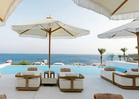 Poolbereich mit Sitzgelegenheiten und Sonnenschirmen.