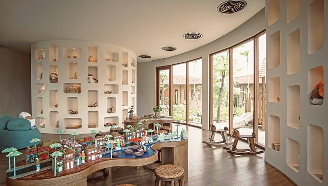 Kinderbereich mit Spielmöbeln, bunten Figuren und großen Fenstern