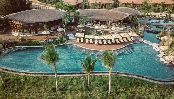 Weitläufige Poollandschaft mit Liegen, Palmen und organischen Formen