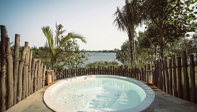 Runder Jacuzzi im Freien mit Holzumzäunung und Flussblick