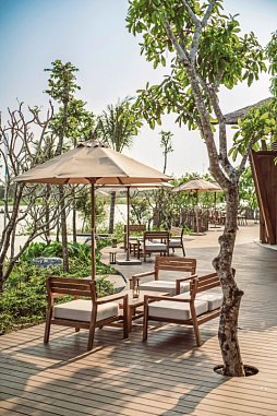 Holzterrasse mit Sonnenschirmen, Stühlen und Gartenblick