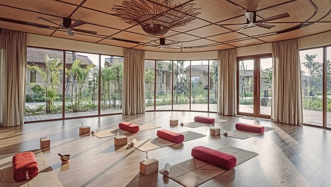 Heller Raum mit Yogamatten, großen Fenstern und Gartenblick