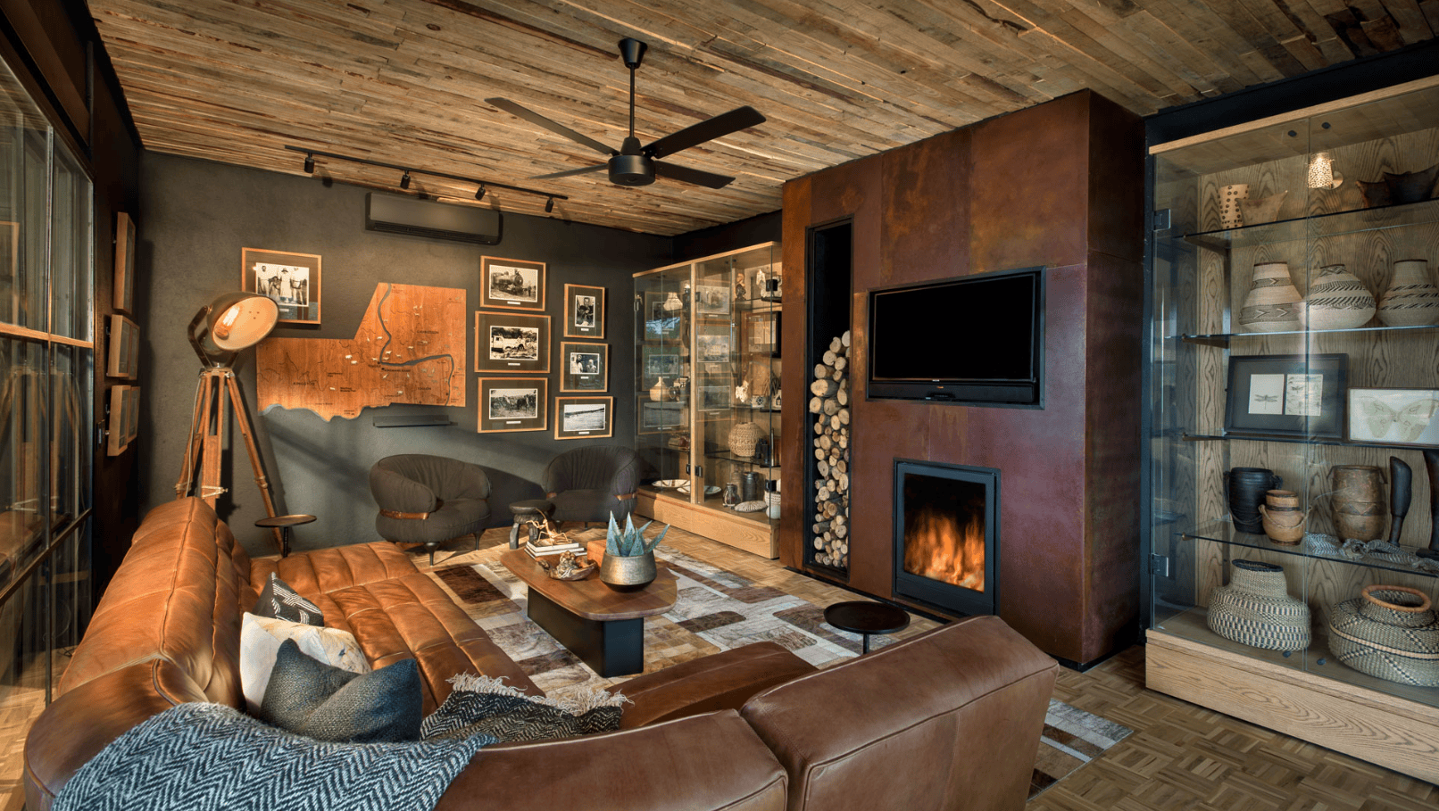 Stilvoller Aufenthaltsraum mit Kamin, Ledersofa und afrikanischen Kunstobjekten