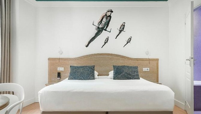 Hotelzimmer mit großem Doppelbett, Wandgrafik eines Fliegers und modernem, schlichtem Interieur im Hotel The Originals Boutique