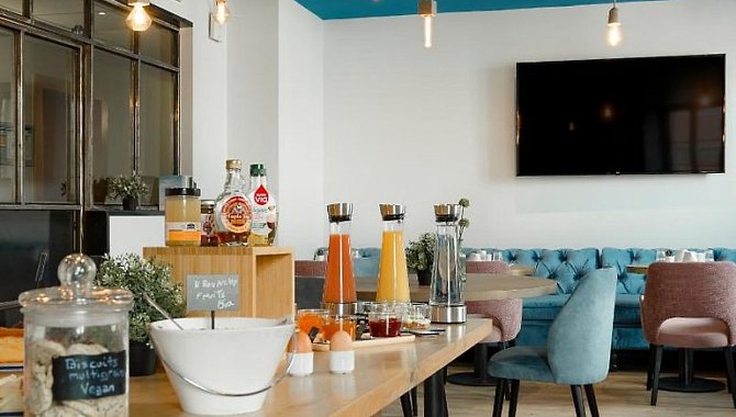 Frühstücksraum mit Saftstation, Kaffeemaschine und modernem Mobiliar im Hotel The Originals Boutique