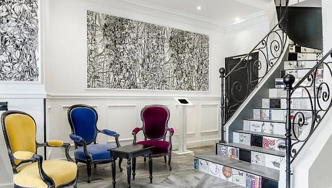 Lounge- oder Wartebereich mit bunt gepolsterten Sesseln und kunstvoll dekorierter Treppe im Hotel The Originals Boutique