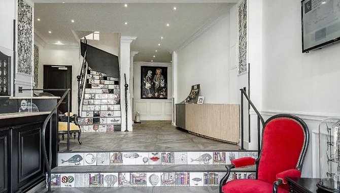 Eingangsbereich mit Rezeption, stilvoller Wandkunst und dekorativer Treppenverkleidung im Hotel The Originals Boutique