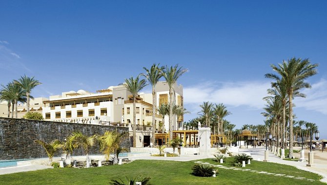 Das Hotelgebäude in Weiß. Davor eine große grüne Wiese.