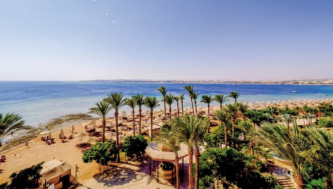 Vogelperspektive auf das Hotel. Viele Palmen und das Meer.