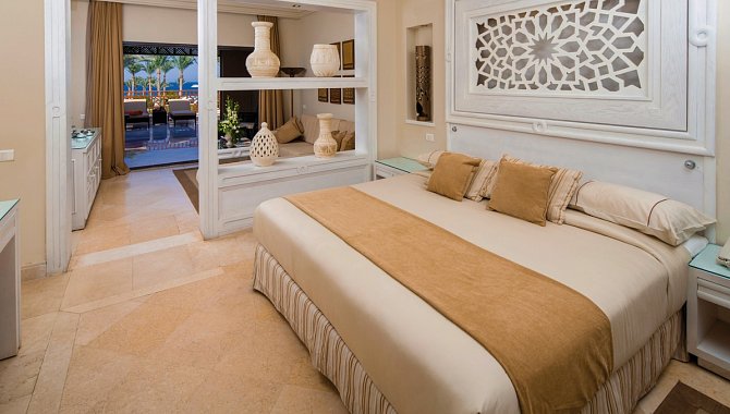 Großes Bett in der Juniorsuite. Wände aus weißem Holz, die Einrichtung ist in hellen Cremefarben gehalten.