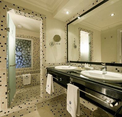 Badezimmer des Hotels mit großem Spiegel, zwei Waschbecken. Alles in Schwarz weiß gehalten.