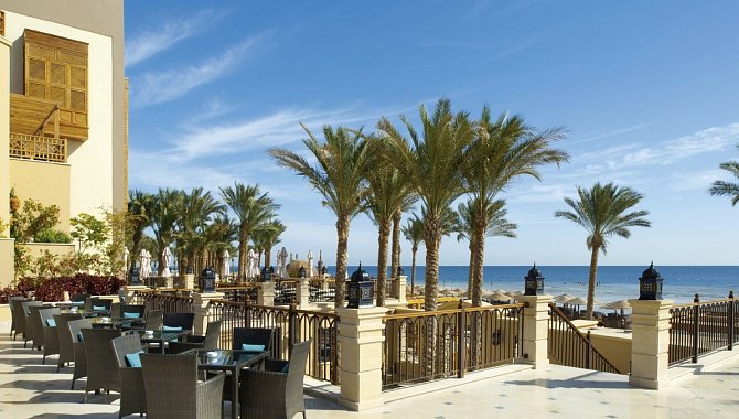 Hotel Terrasse mit Tischen für jeweils 4 Personen. Direkt dahinter der Sandstrand mit Plamen.