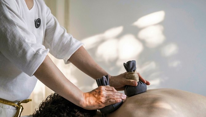 Wellness-Massage mit Kräuterstempeln auf dem Rücken