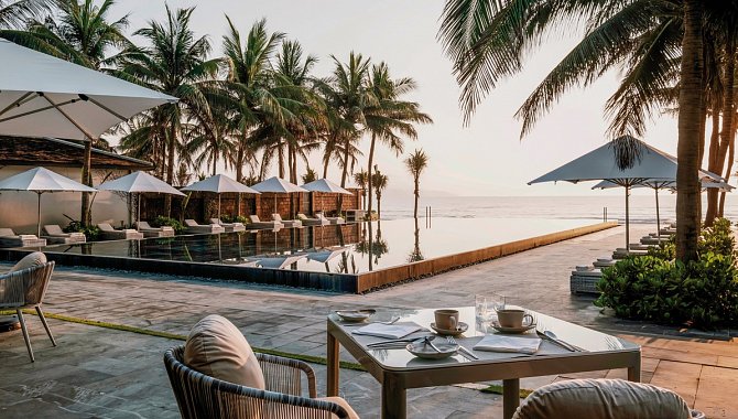 Frühstückstisch auf einer Terrasse mit Blick auf den Infinity-Pool und das Meer.