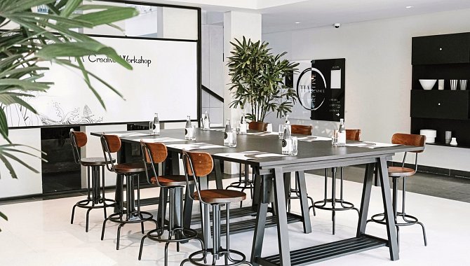 Moderner Workshopraum mit hohem Tisch, Barhockern und minimalistischer Einrichtung