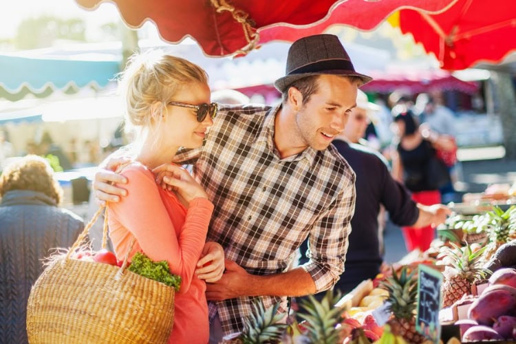 Paar steht vor einem Obststand auf einem Marktplatz